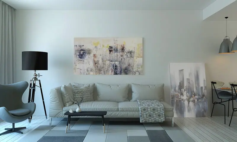 Sala com sofá claro, mesa de centro, luminária de tripé e quadros na parede