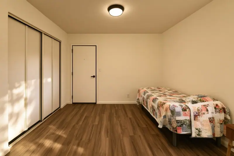 Quarto simples com cama de solteiro, armário embutido e porta fechada