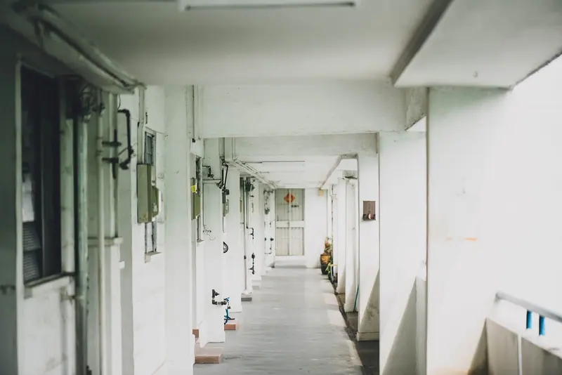 Corredor comprido de um prédio residencial, com portas de apartamentos dos dois lados