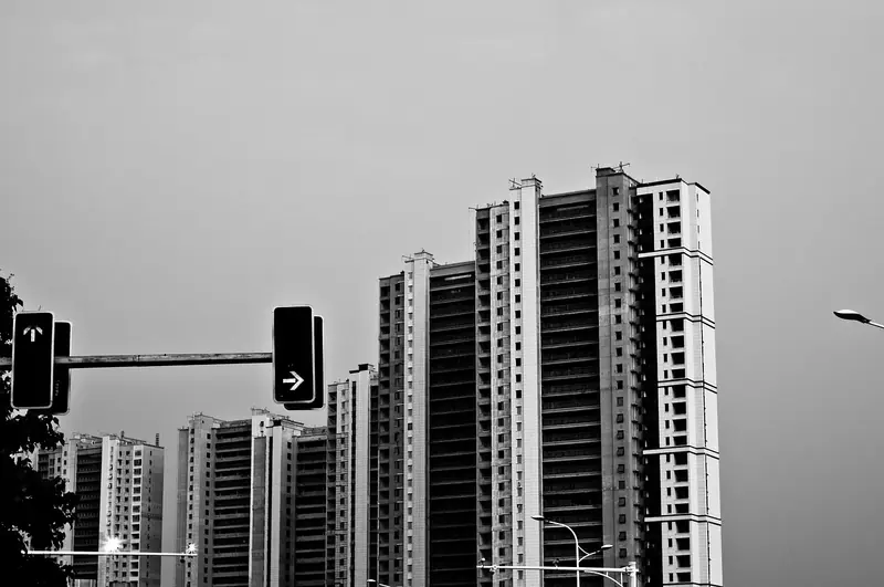 Prédios residenciais altos ao lado de um semáforo, em preto e branco