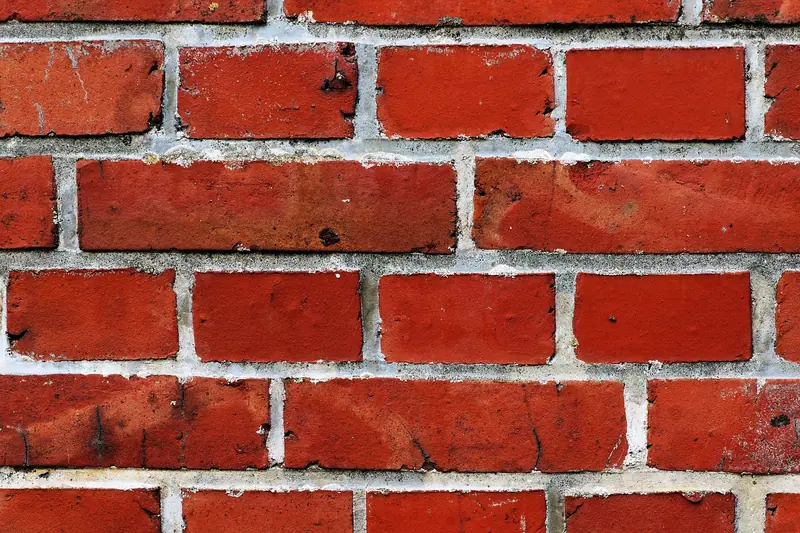 Tijolos vermelhos alinhados com argamassa cinza, vistos de perto