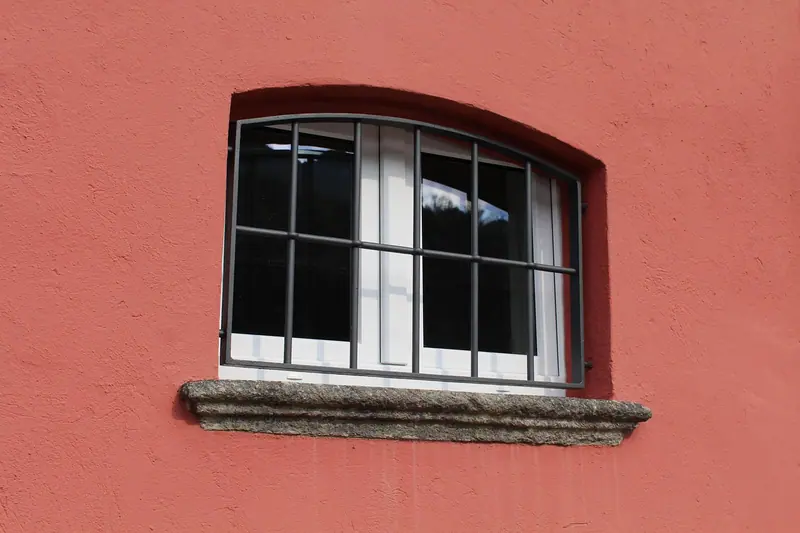 Janela com grade de ferro numa parede vermelha de casa