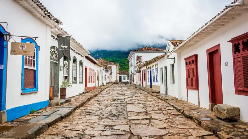 Rua de pedra com casas térreas coloridas, com portas e janelas voltadas direto para a calçada