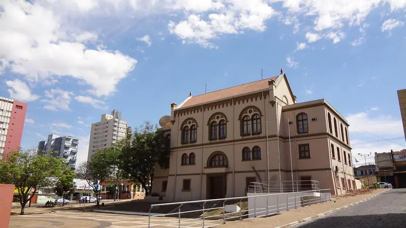 Prédio histórico de dois andares com janelas em arco, ao lado de prédios residenciais em São Paulo