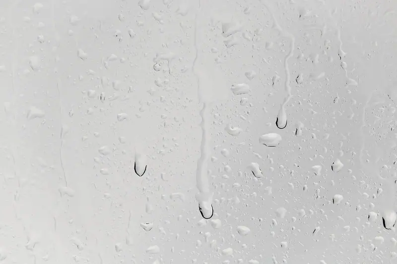 Gotas de água escorrendo devagar num vidro claro e liso