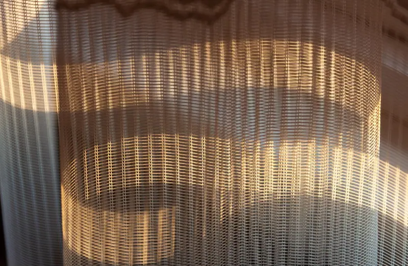 Cortina fina e franzida com faixas de luz do sol desenhadas no tecido