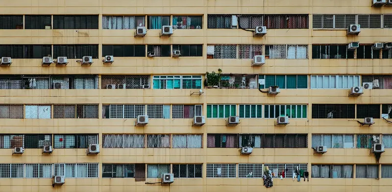 Fachada de prédio residencial com várias janelas e aparelhos de ar-condicionado do lado de fora