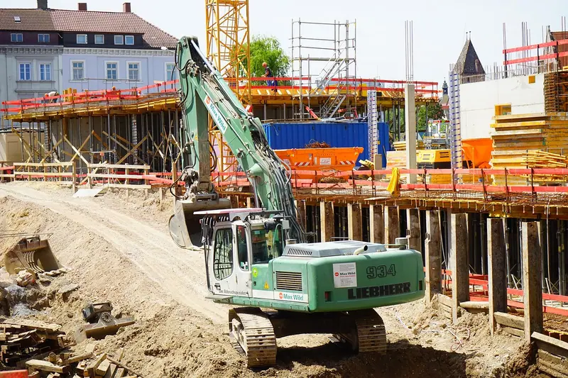 Escavadeira trabalhando no terreno de uma obra, com prédios em volta