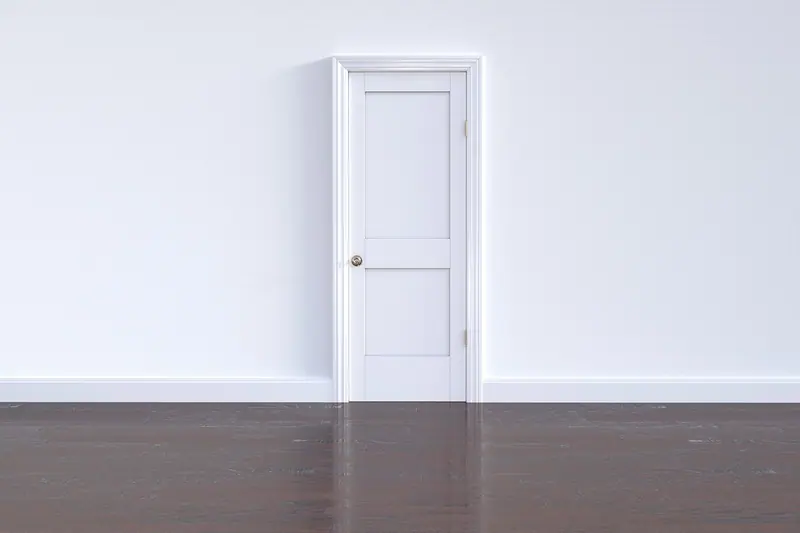 Porta branca fechada numa parede clara, com piso de madeira escura
