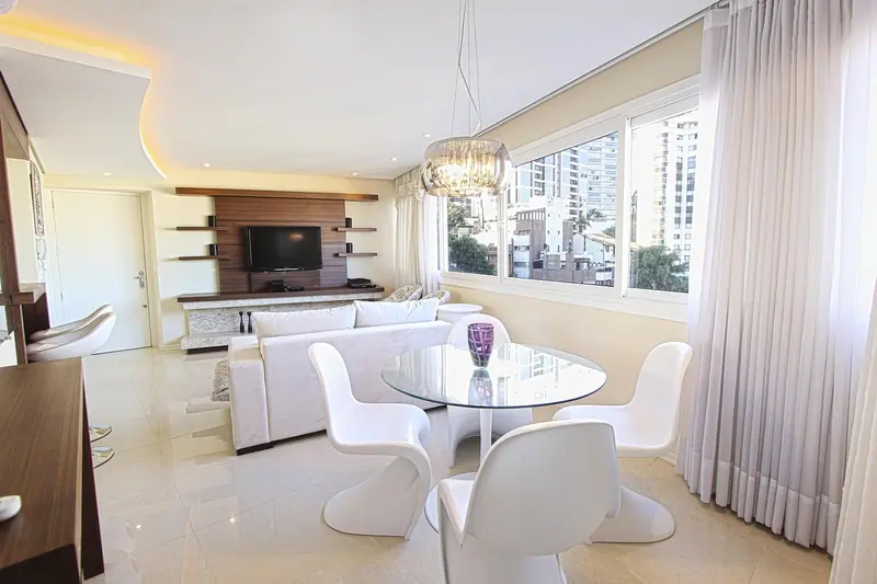 Sala de apartamento com janelas amplas e prédios vizinhos do lado de fora