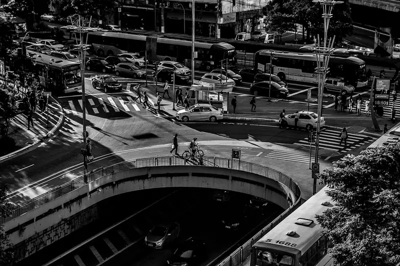 Cruzamento movimentado em São Paulo visto do alto, com ônibus e carros, em preto e branco
