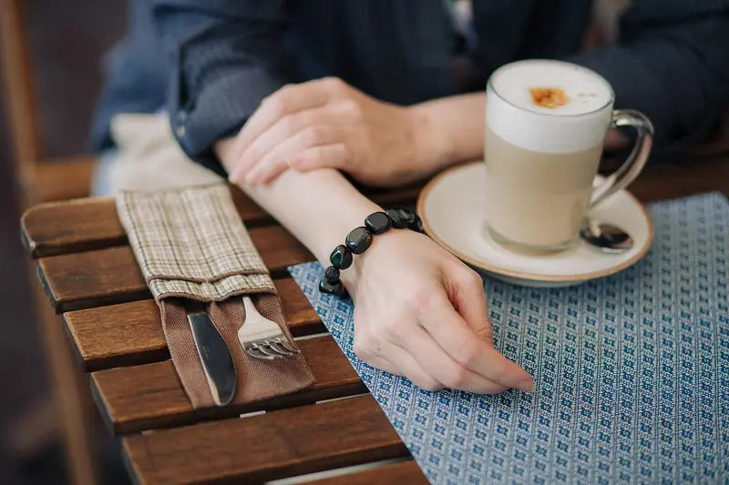 Mãos de duas pessoas sobre uma mesa de madeira, com uma xícara de café, durante uma conversa