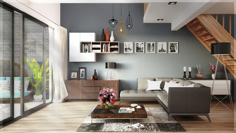 Sala de estar com sofá cinza, estante na parede e porta de vidro com cortina leve ao lado