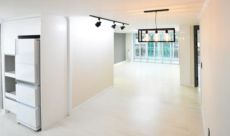 Apartamento claro e vazio, com piso de madeira e uma parede de vidro ao fundo