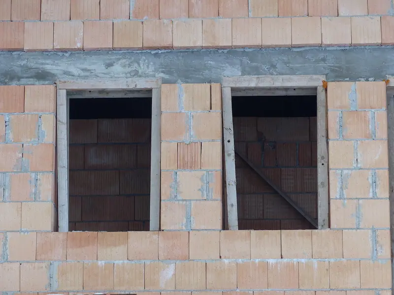 Parede de blocos cerâmicos em construção com dois vãos de janela ainda sem esquadria