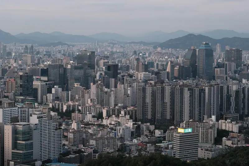 Cidade densa de prédios vista do alto, com morros ao fundo num dia nublado