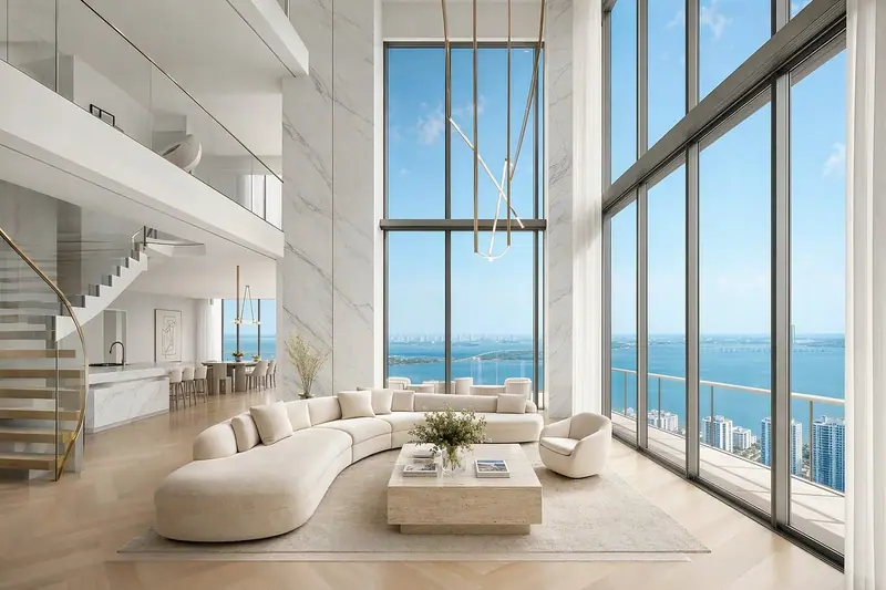 Sala ampla e clara com sofá curvo branco e janelas altas do piso ao teto com vista para o mar