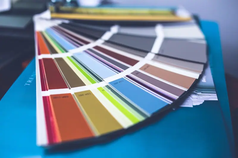 Leque de amostras de cores aberto sobre uma superfície azul, com o fundo desfocado