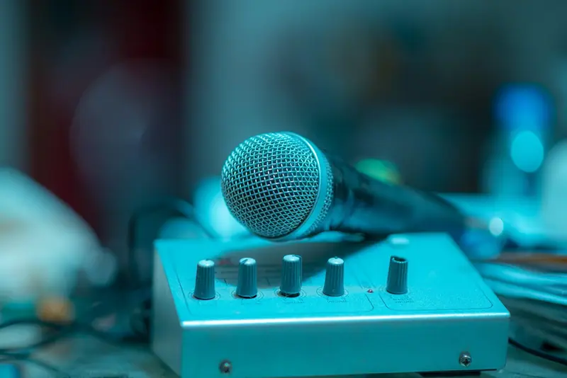 Microfone apoiado sobre um pequeno amplificador com botões, sob luz azul