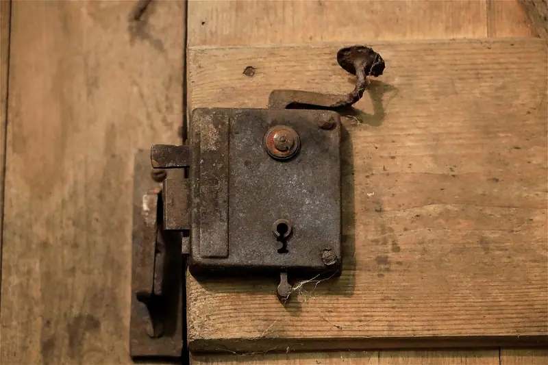 Fechadura antiga de metal presa numa porta de madeira, em close