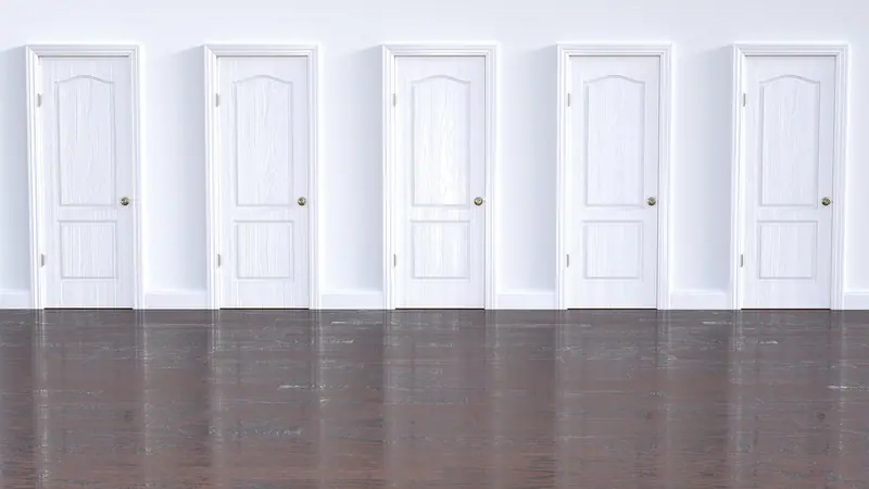 Fileira de cinco portas brancas iguais numa parede clara, com piso escuro
