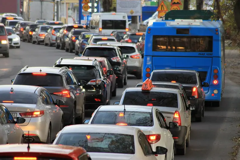 Trânsito parado numa avenida, com carros enfileirados e um ônibus azul na faixa ao lado