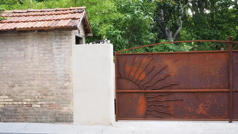 Muro claro com um portão de chapa de metal enferrujada, inteiro e fechado