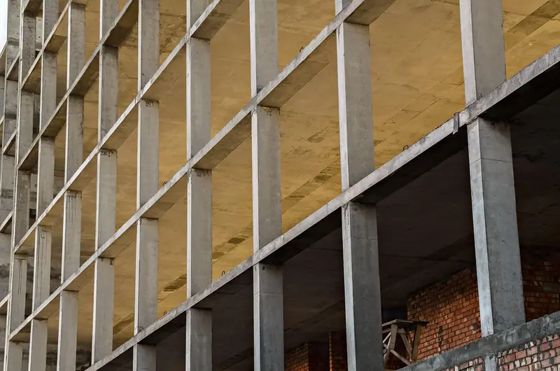 Prédio em obra com a estrutura de concreto aparente, lajes e pilares formando uma grade