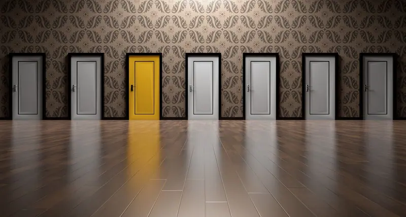 Fileira de portas cinza com uma porta amarela no meio, numa parede de papel estampado