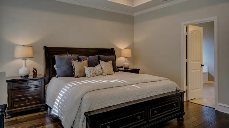 Quarto com cama de casal, abajures, ventilador de teto e uma porta branca aberta ao lado