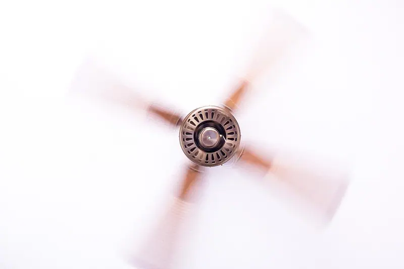 Ventilador de teto girando, visto de baixo contra um teto branco