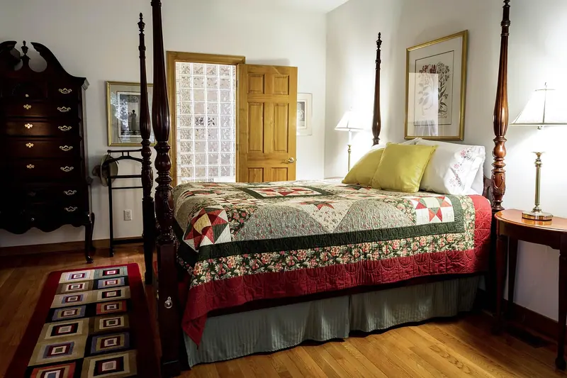 Quarto com cama de dossel, cômoda escura e porta de madeira entreaberta