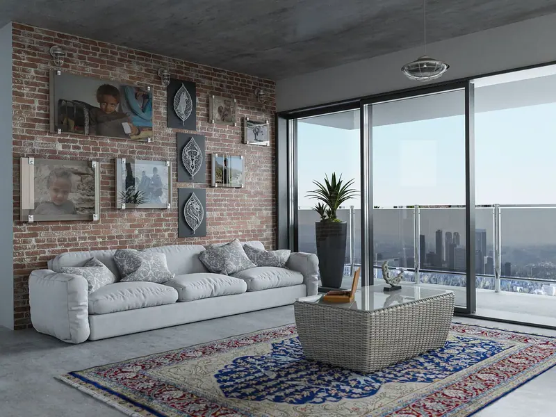Sala de apartamento com sofá branco e porta de vidro de correr para a sacada, com prédios ao fundo