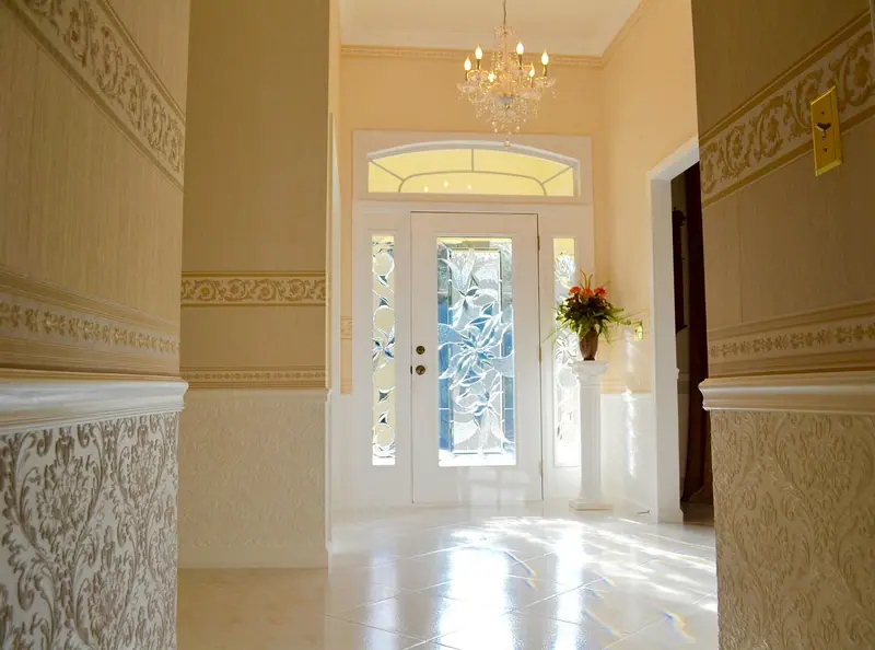 Hall de entrada com porta branca de vidro decorado, vidros laterais e lustre no teto