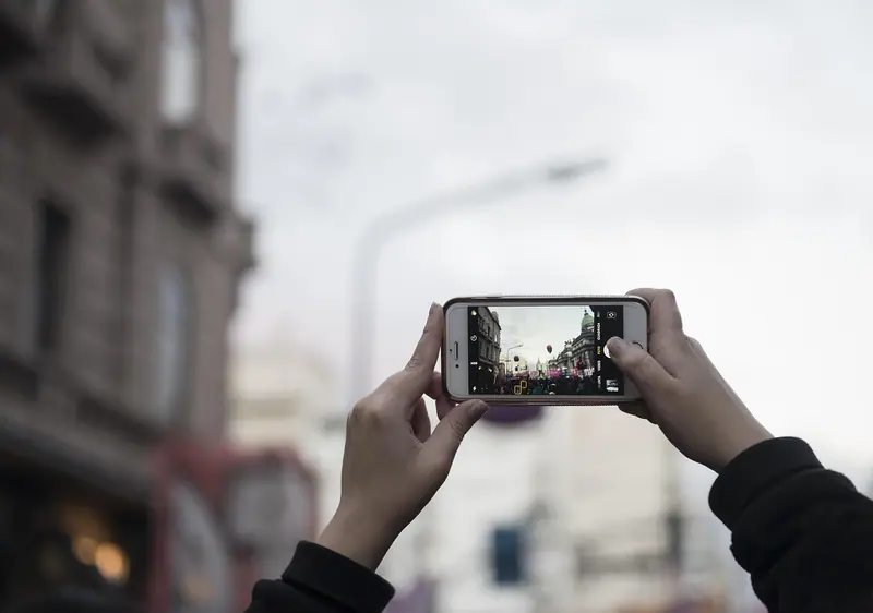 Mãos segurando um celular na horizontal para tirar uma foto