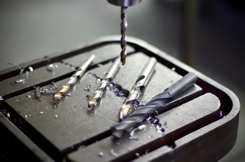 Brocas e aparas de metal sobre a mesa de uma furadeira de bancada
