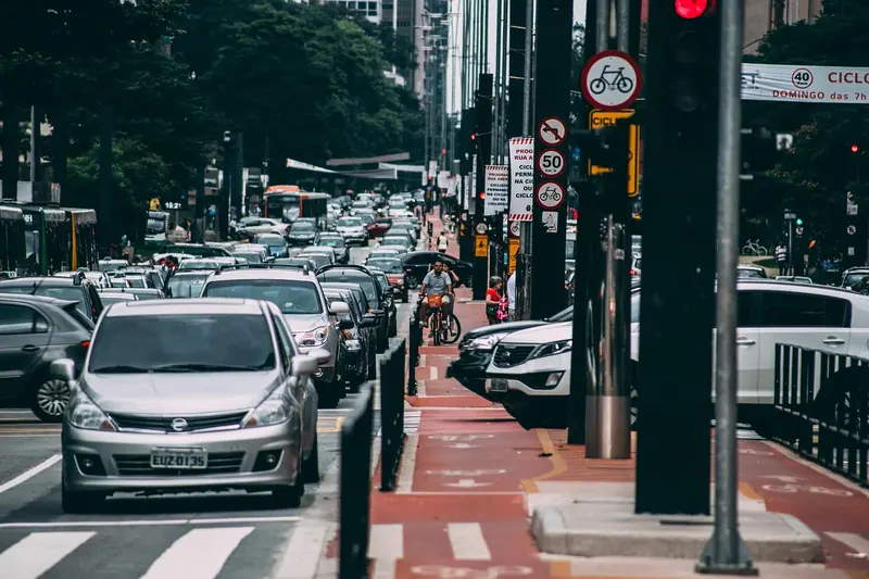Carros enfileirados numa avenida de São Paulo, ao lado de uma ciclovia