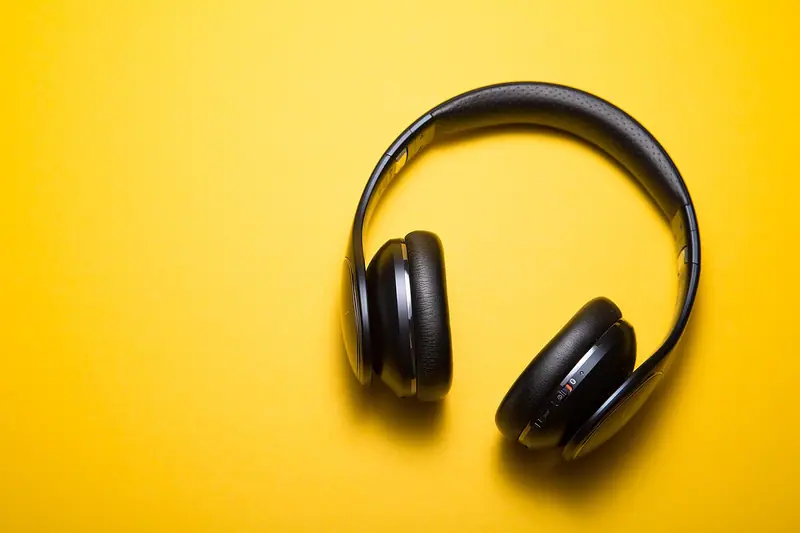 Fone de ouvido preto, do tipo que cobre as orelhas, sobre um fundo amarelo