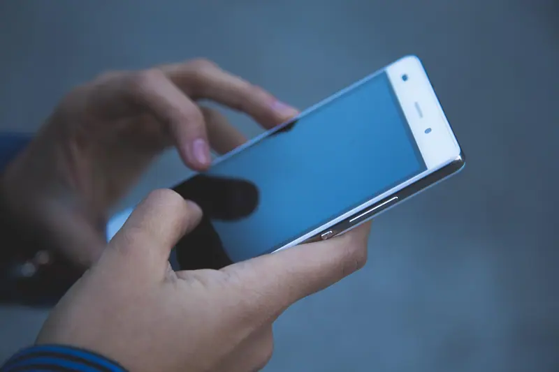 Mãos segurando um celular e digitando uma mensagem