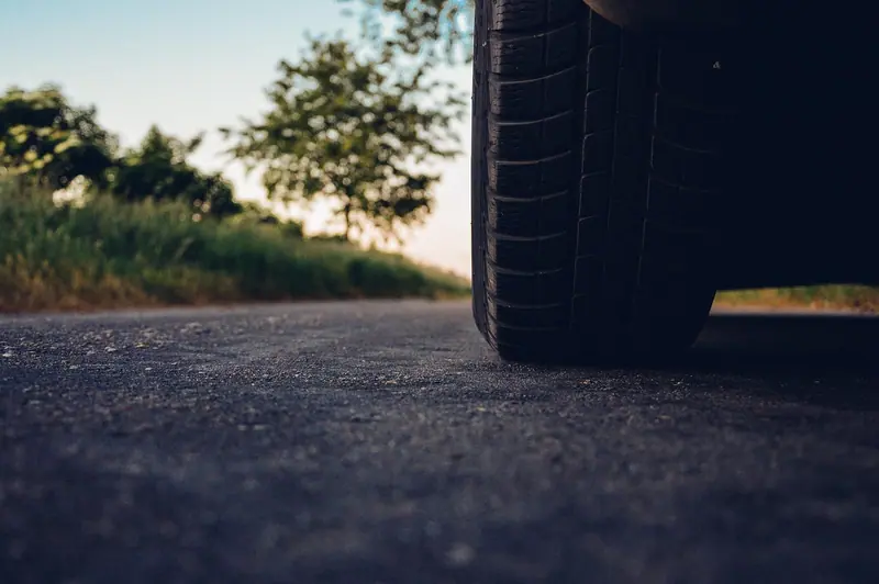 Pneu de carro sobre uma estrada de asfalto, fotografado bem rente ao chão