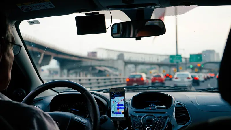 Celular com um mapa de rota preso ao painel de um carro, com o trânsito e um viaduto à frente