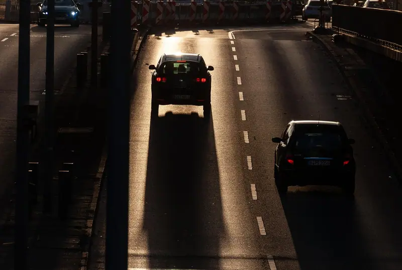 Carros com faróis acesos numa avenida à noite, vistos de cima
