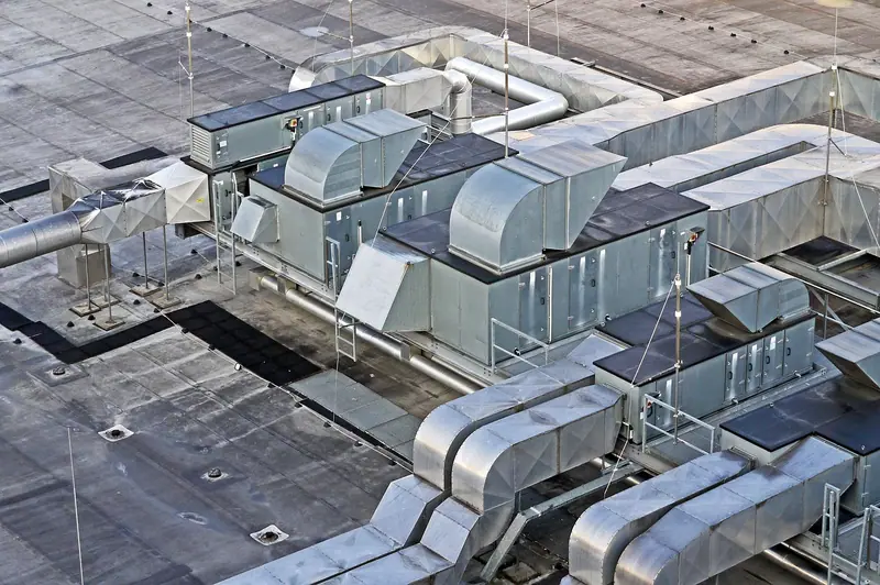 Equipamentos e dutos metálicos de ventilação e ar-condicionado instalados sobre o telhado de um prédio