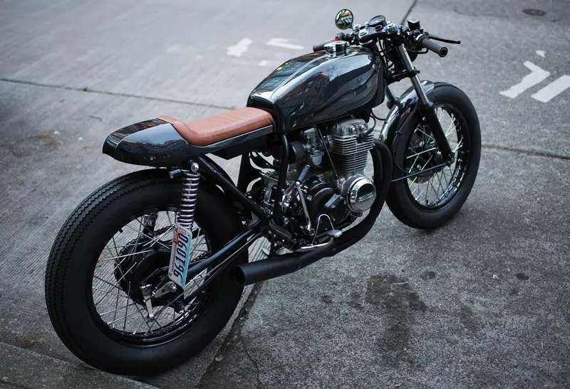 Motocicleta escura estacionada numa rua de asfalto