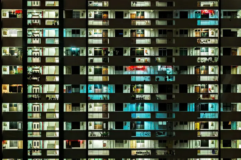 Fachada de prédio residencial à noite, com muitas janelas acesas