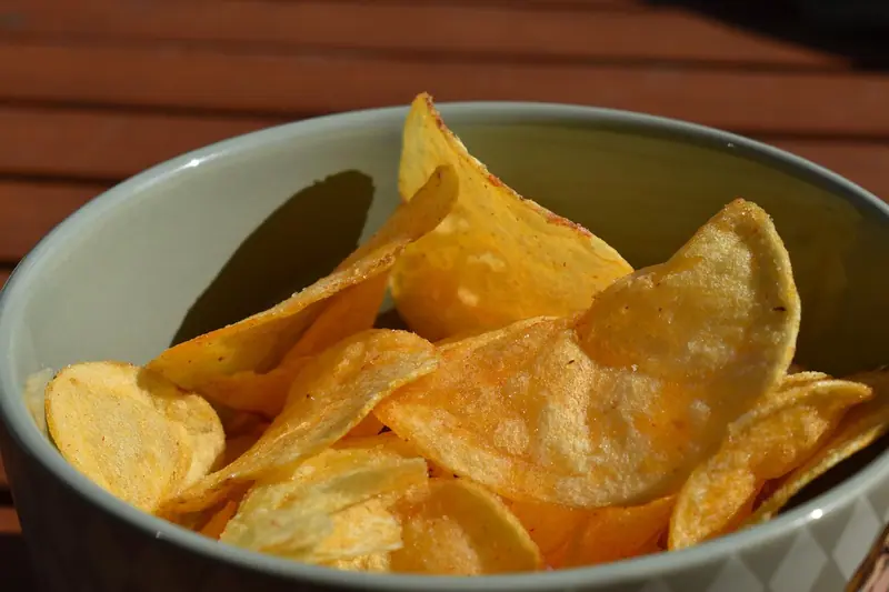 Tigela cheia de batatas chips douradas sobre uma mesa