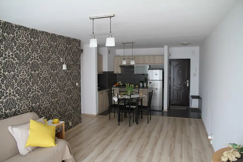 Sala integrada com cozinha compacta e a porta de entrada escura do apartamento ao fundo