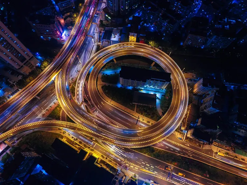 Viadutos e avenidas iluminados por faróis à noite, vistos do alto entre prédios