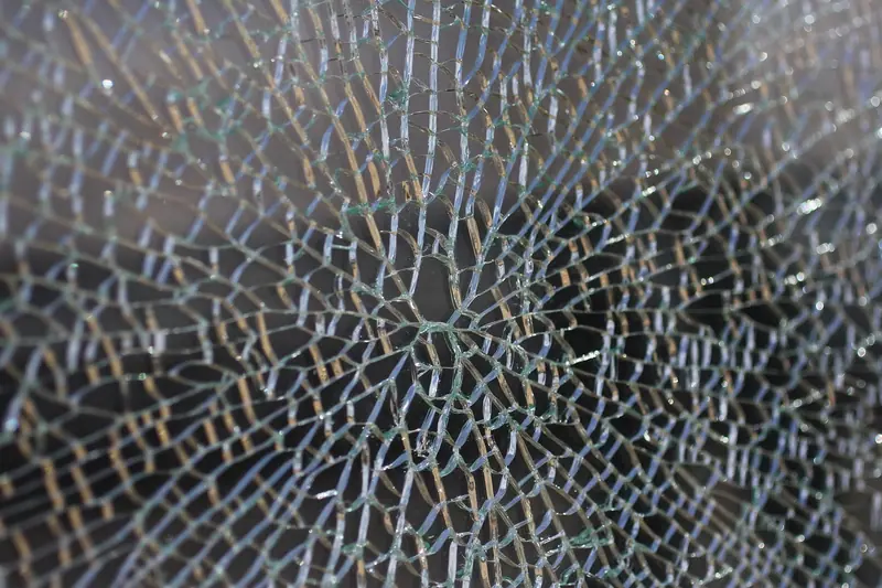 Vidro todo rachado em pequenos pedaços que continuam unidos na chapa