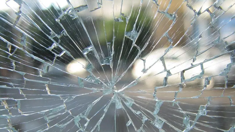 Vidro trincado em forma de teia, com as rachaduras espalhadas a partir de um ponto e a chapa ainda inteira